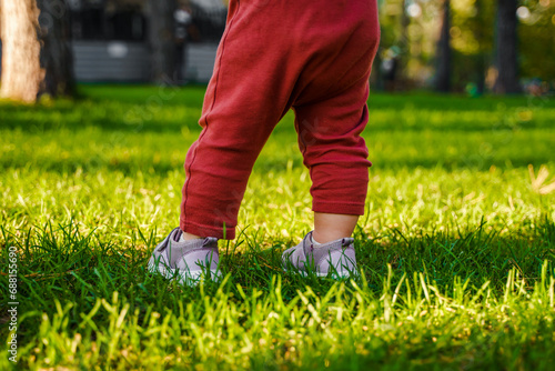Cute child girl baby toddler walks on the green grass at sunset