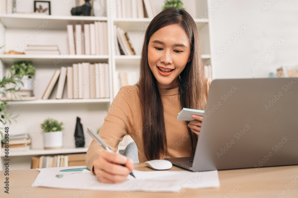 Beautiful young woman using laptop while working in home office. Businesswoman happy and smiling at indoors. Beautiful young woman using laptop while working in home office. Businesswoman happy and smiling at indoors.