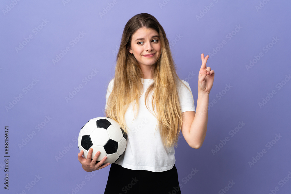 Young blonde football player woman isolated on purple background with fingers crossing and wishing the best Young blonde football player woman isolated on purple background with fingers crossing and wishing the best