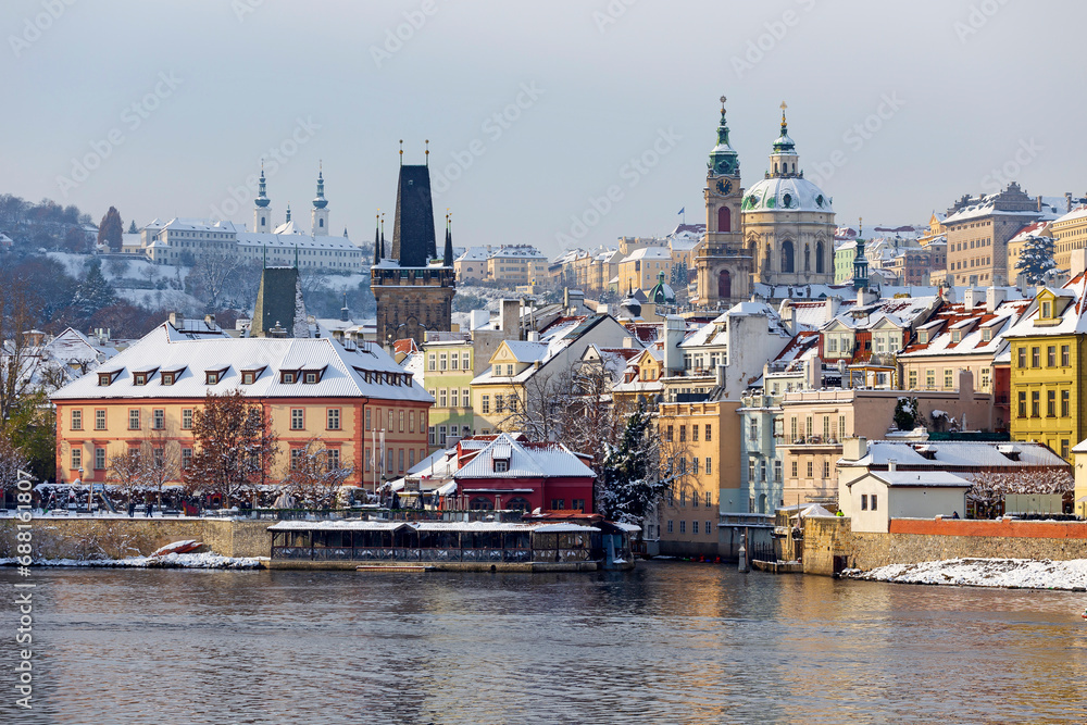 Snowy Prague Lesser Town with St. Nicholas' Cathedral above River Vltava, Czech republic