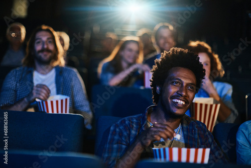 Smiling young man watching movie at the cinema