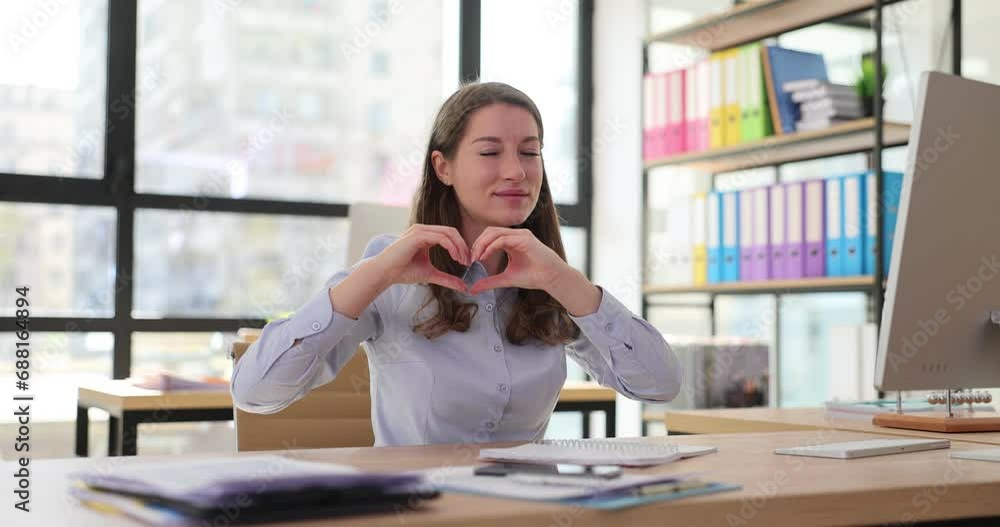 Positive female employee shows heart shape with hands Positive female employee shows heart shape with hands