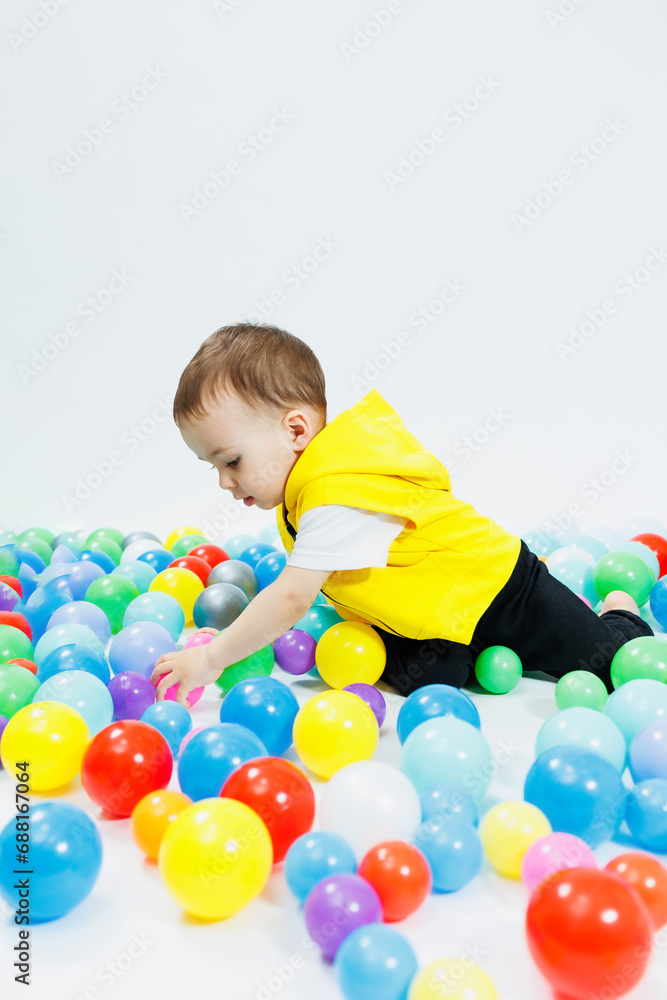 Happy boy in colorful balls in children's playgroup. the child smiles, hiding in the balls.