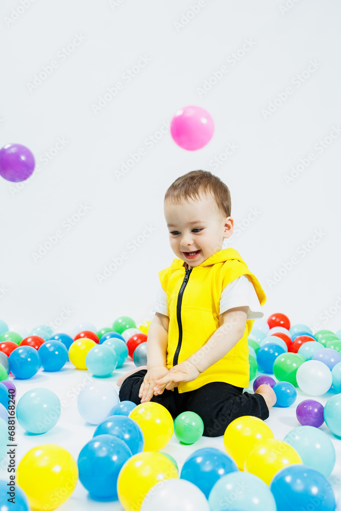 Happy boy in colorful balls in children's playgroup. the child smiles, hiding in the balls. Happy boy in colorful balls in children's playgroup. the child smiles, hiding in the balls.