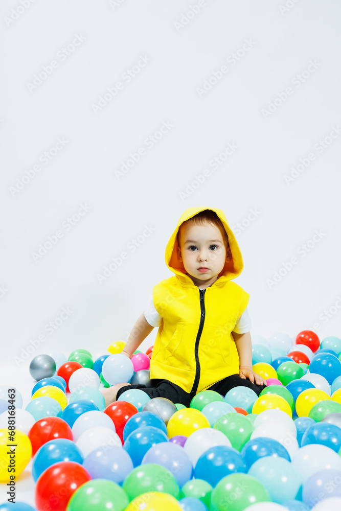 Happy boy in colorful balls in children's playgroup. the child smiles, hiding in the balls. Happy boy in colorful balls in children's playgroup. the child smiles, hiding in the balls.