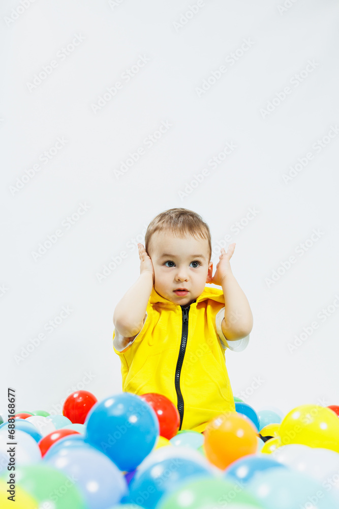 Happy boy in colorful balls in children's playgroup. the child smiles, hiding in the balls. Happy boy in colorful balls in children's playgroup. the child smiles, hiding in the balls.
