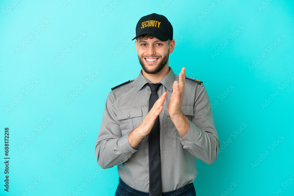 Young security man isolated on blue background applauding after presentation in a conference Young security man isolated on blue background applauding after presentation in a conference