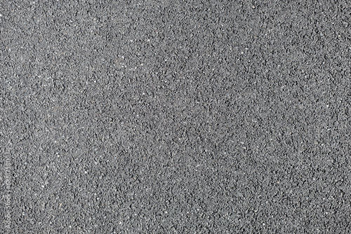 A frame filled with the textured surface of dry asphalt, showcasing the detailed pattern and composition under the sunlight on a clear day. photo