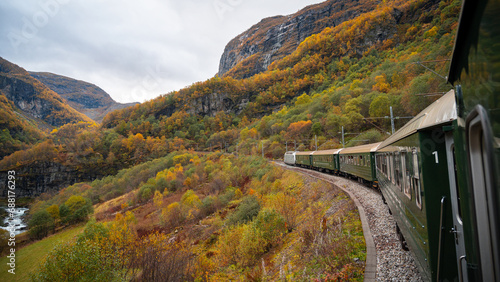 Side view of a train running on a track on a hairpin bend in the fjord mountains of Norway in autumn.