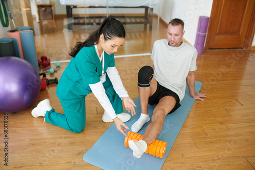 Nurse explaining patient how to do myofascial release with foam roller photo
