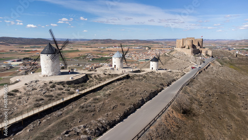 Old windmills in line with the Castillo de la Muela in the background, in the town of Consuegra located in the province of Toledo, Spain photo