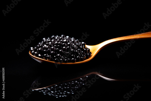 Closeup of natural black caviar on a golden spoon on black background, texture of fresh sturgeon caviar macro photo.