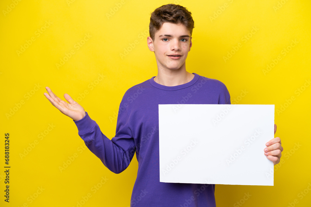 Teenager Russian man isolated on yellow background holding an empty placard with surprised expression