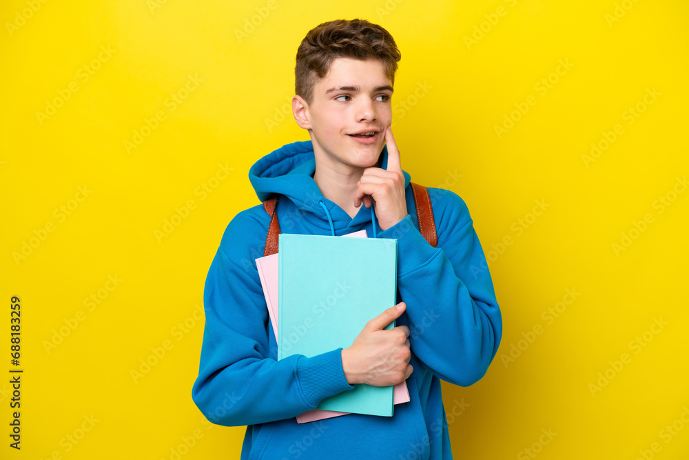 Teenager Russian student man isolated on yellow background thinking an idea while looking up Teenager Russian student man isolated on yellow background thinking an idea while looking up