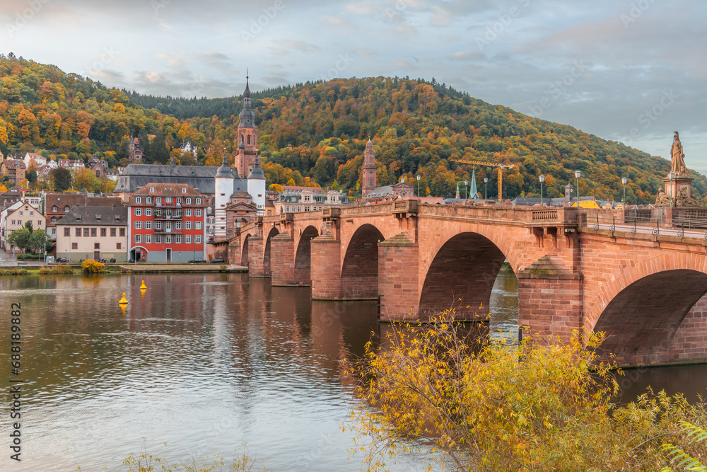 Obraz premium View on the Karl Theodor Bridge (German: Karl-Theodor-Brücke) and the old gate in the german city Heidelberg during early morning on a cloudy day. Heidelberg on Neckar river.
