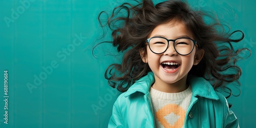 chłopczyk śmiejący się w okularach na niebieskim tłe w czarnych długich włosach
