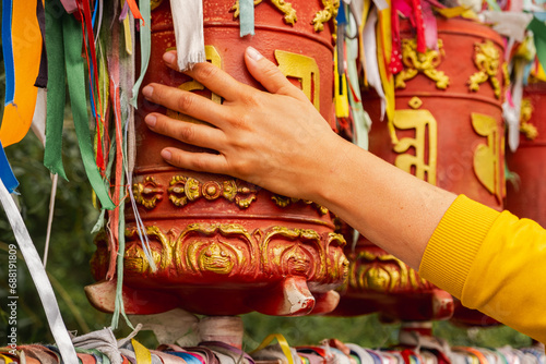 Person pilgrim female hand touching turning spinning Buddhist prayer wheel at Buddhist monastery. Prayer wheels in Buddhist stupa temple. Buddhism religion concept