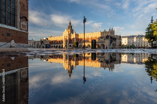 Renaissance Cloth Hall on Krakow Main Square reflecting in the water puddle, sunny morning, Cracow, Poland