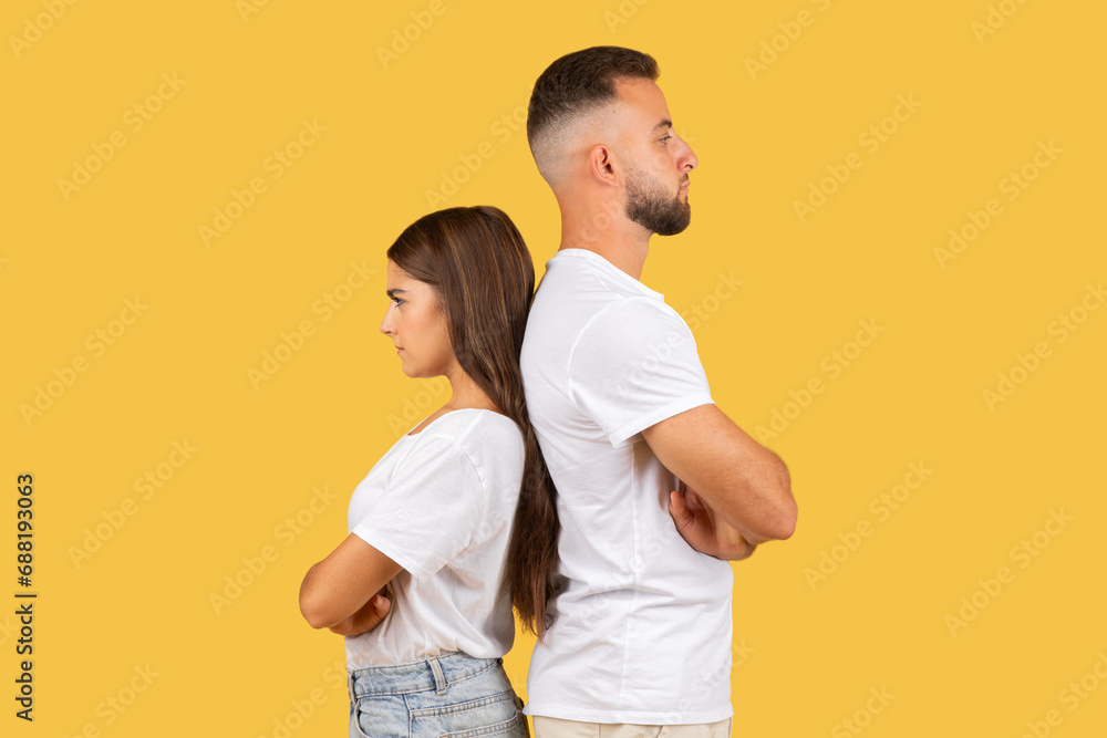 Sad angry millennial european wife and husband in white t-shirts back to back, ignoring after quarrel Sad angry millennial european wife and husband in white t-shirts back to back, ignoring after quarrel