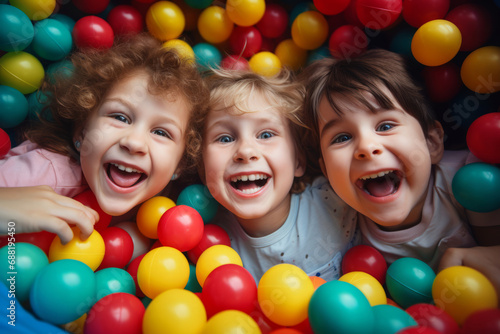 Above view portrait of three happy little children playing ball pit smiling at camera while playing at children's play center, copy space.generative ai
