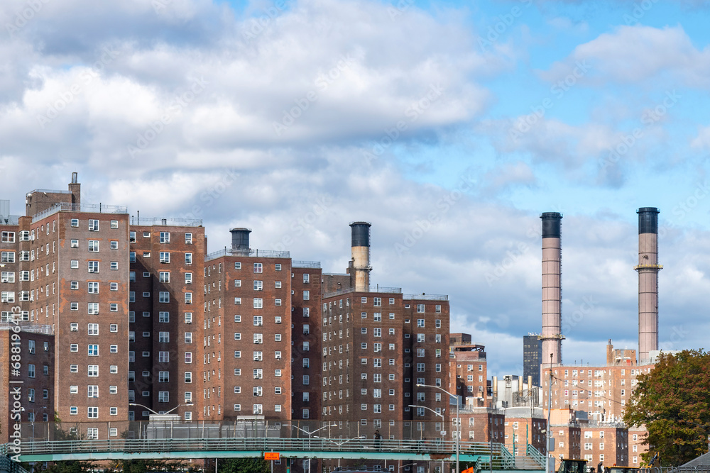 Identical brick apartment blocks in the East Village, New York City, NY, USA along the East river with in the background the smokestacks of the energy plant for the city