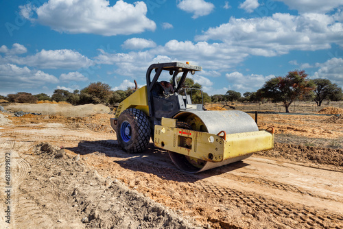 compactor heavy machinery paving a dirt road on a construction site