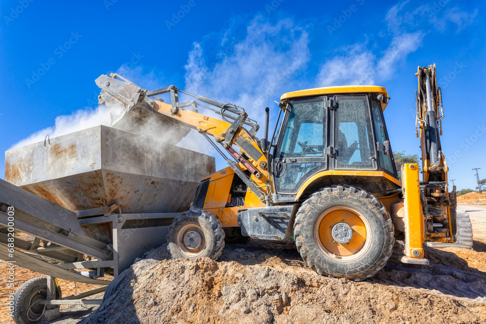 excavator loader backhoe loading a trailer with cement
