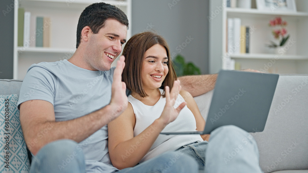 Beautiful couple sitting on sofa together having video call at home Beautiful couple sitting on sofa together having video call at home