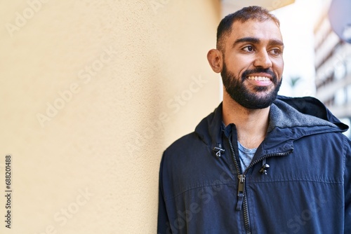 Young hispanic man smiling confident looking to the side at street