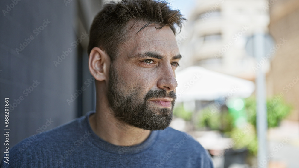 Cool and handsome young hispanic man, with a relaxed lifestyle, photographed outdoors with a serious expression, looking to the side on a sunny urban street. Cool and handsome young hispanic man, with a relaxed lifestyle, photographed outdoors with a serious expression, looking to the side on a sunny urban street.