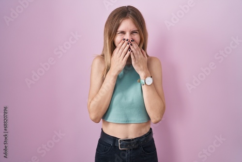 Schilderij op canvas Blonde caucasian woman standing over pink background laughing and embarrassed gi