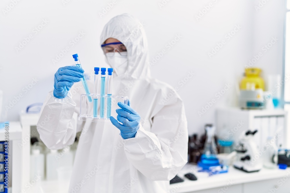 Young blonde woman scientist wearing security uniform holding test tubes at laboratory Young blonde woman scientist wearing security uniform holding test tubes at laboratory