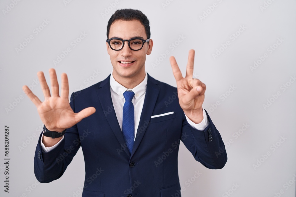 Young hispanic man wearing suit and tie showing and pointing up with fingers number seven while smiling confident and happy. Young hispanic man wearing suit and tie showing and pointing up with fingers number seven while smiling confident and happy.