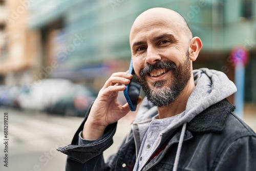 Young bald man smiling confident talking on the smartphone at street