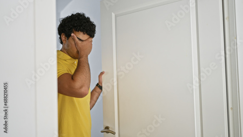 Young latin man opening door worried at home