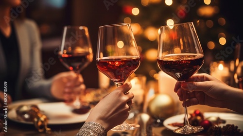 Women friends during a party with clinking glasses of red wine at the festive table with wishes of happiness