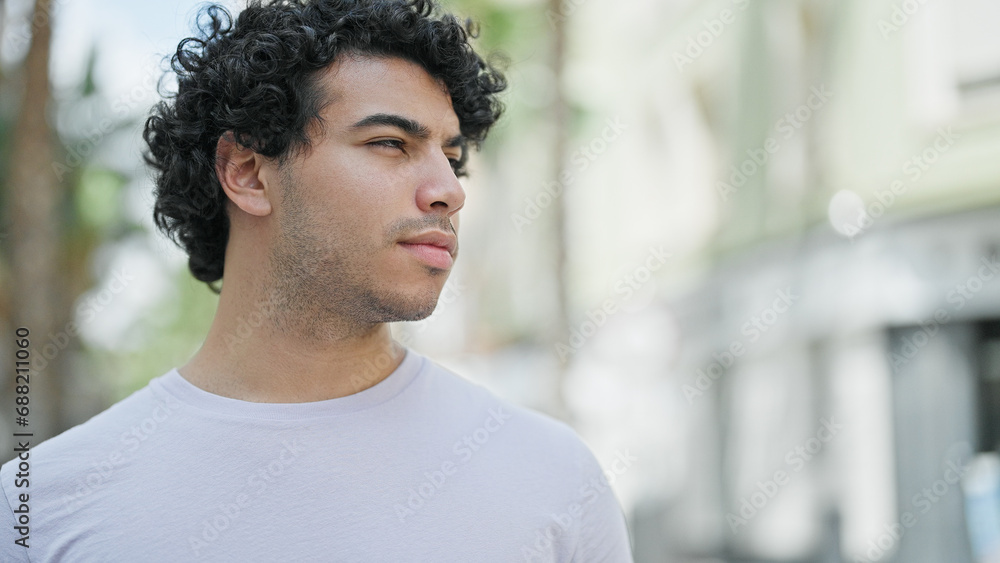 Young latin man looking to the side with serious expression at street Young latin man looking to the side with serious expression at street