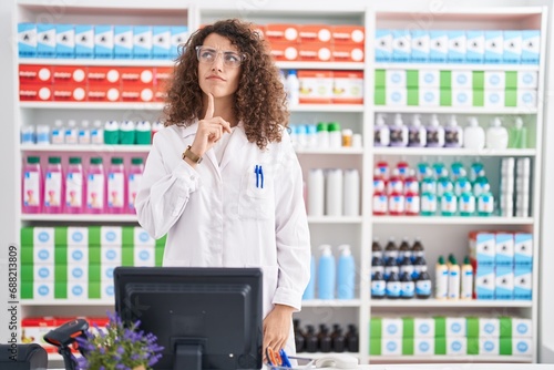 Obraz na plátně Hispanic woman with curly hair working at pharmacy drugstore thinking concentrat