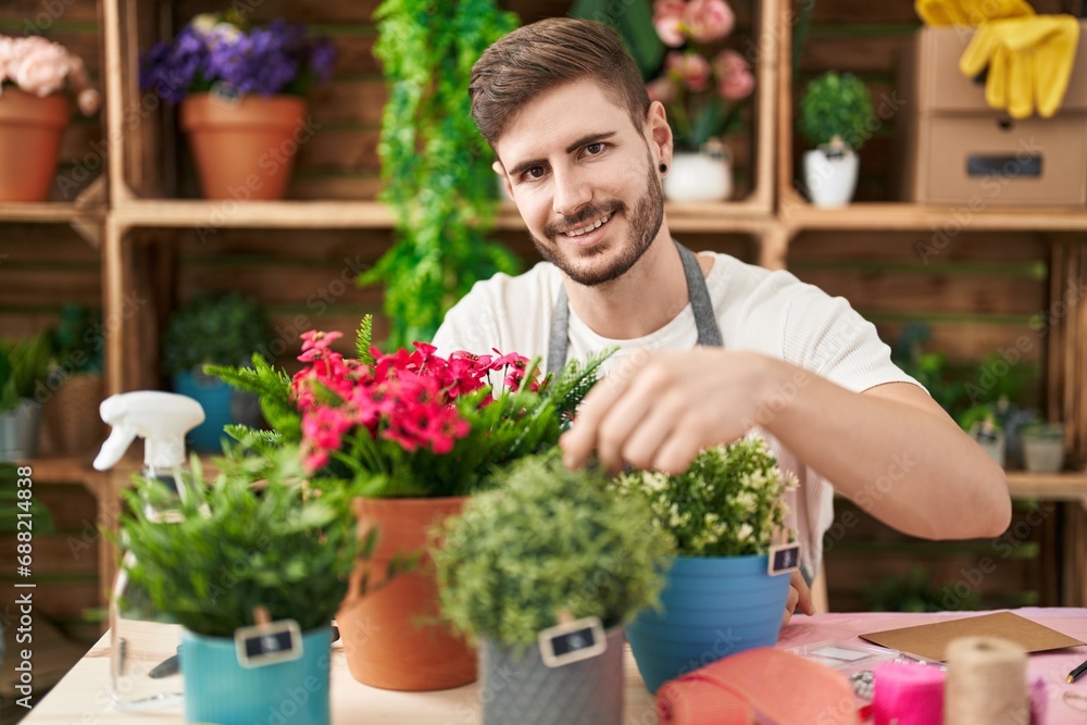 Young caucasian man florist smiling confident touching plant at flower shop