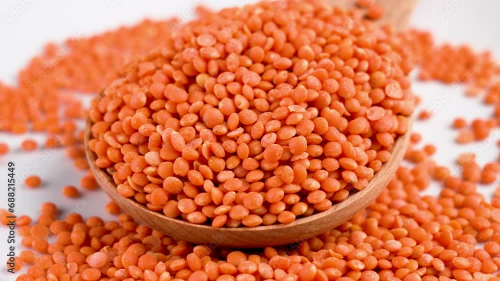 Full wooden rustic spoon with uncooked red lentils. Organic legume grains close up. High vegetable protein product. Rotation Full wooden rustic spoon with uncooked red lentils. Organic legume grains close up. High vegetable protein product. Rotation