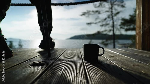 Person Resting On Balcony In Morning, Closeup View Of Male Legs And Cup Of Coffee On Floor