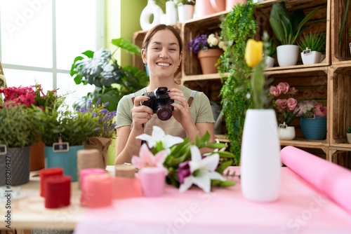 Young beautiful woman florist make photo to bouquet of flowers at flower shop photo
