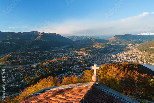 Wide-angle sunset view from the summit of Monte San Salvatore overlooking Lake Lugano Breathtaking panorama of the city, Melide causeway and the Swiss Alps in Ticino, Switzerland - November 2023