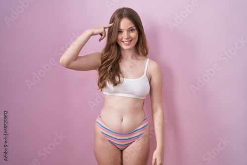 Caucasian woman wearing lingerie over pink background smiling pointing to head with one finger, great idea or thought, good memory