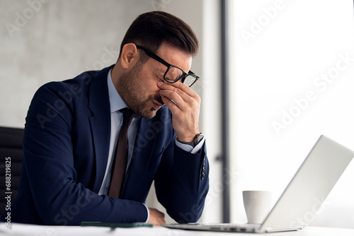 Stressed businessman while working on laptop at office photo