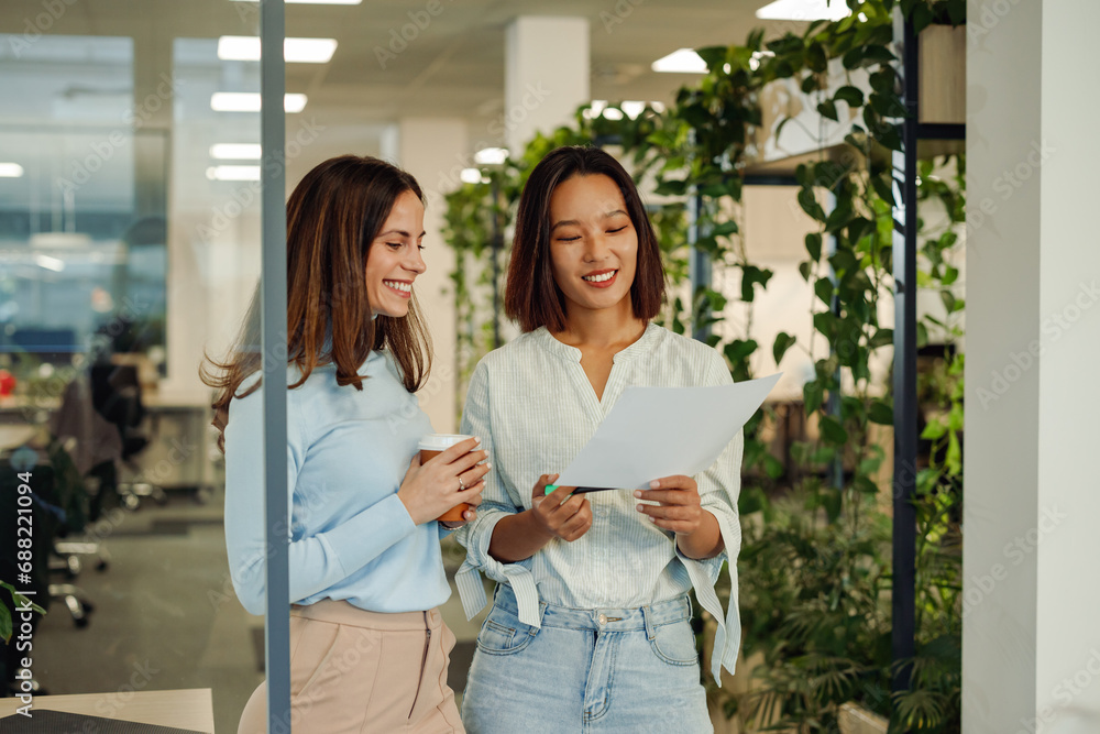 Multiracial woman looking into documents and drinking coffee in the office Multiracial woman looking into documents and drinking coffee in the office
