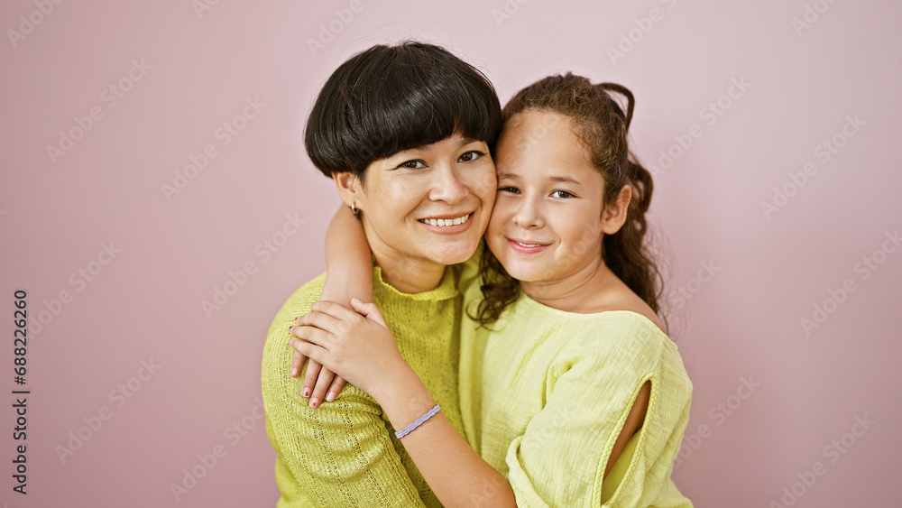 Confident mother and daughter sharing a lovely, happy hug while smiling and standing together over an isolated pink background, expressing a casual lifestyle full of fun, joy and positive vibes. Confident mother and daughter sharing a lovely, happy hug while smiling and standing together over an isolated pink background, expressing a casual lifestyle full of fun, joy and positive vibes.