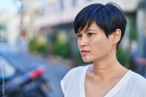 Middle age chinese woman looking to the side with serious expression at street