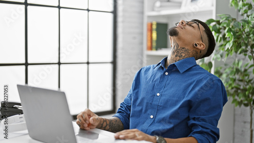 Stressed young latin business worker, man sweating bullets overwork using laptop at office desk. photo