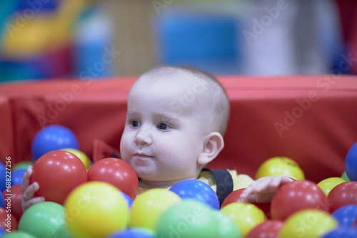 a one-year-old child, a boy, a joyful kid in toys, a lot of balls